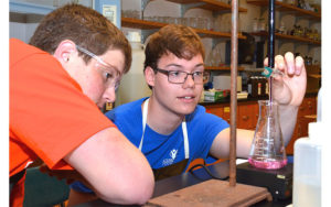 George, who was born with a leg-length discrepancy, with a fellow student in the chemistry lab