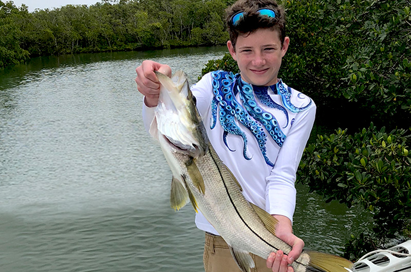 Caden, who had a limb difference caused by a lawnmower accident, holds up a big fish.