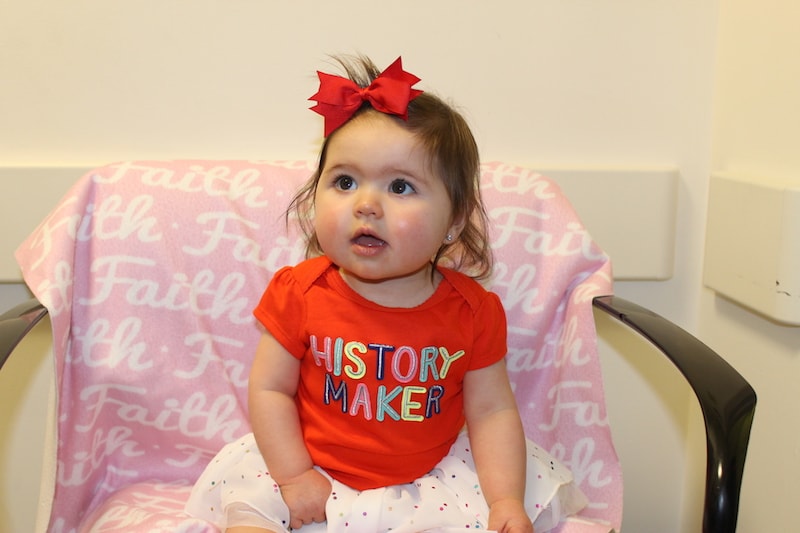 Faith, who had surgery using her own umbilical cord, smiles in a chair