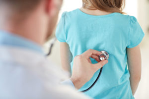 A doctor touches a stethoscope to a child's back