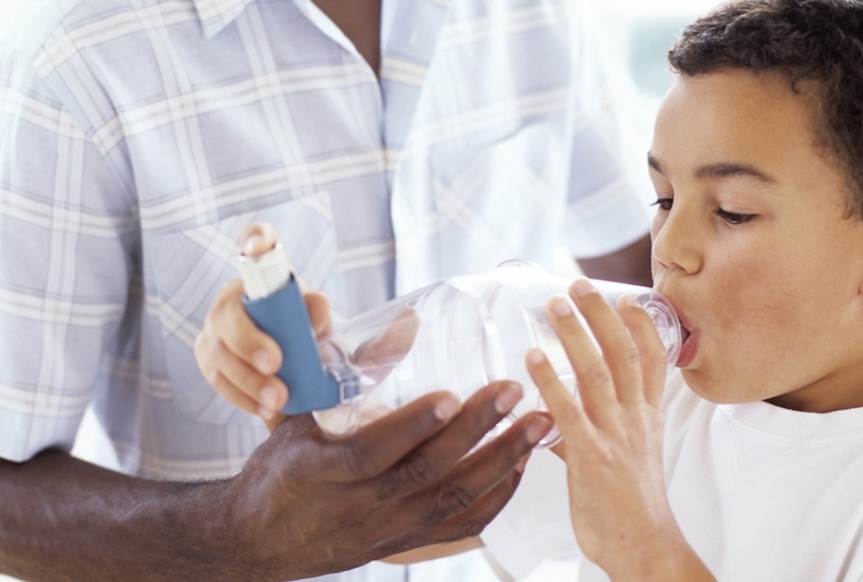 A young boy using an inhaler with spacer