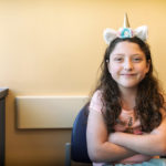 girl taking teduglutide poses in a unicorn headband