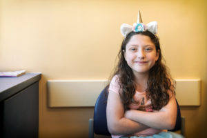 girl taking teduglutide poses in a unicorn headband