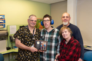 Nicholas, who has Prader-Willi syndrome, and his parents present an award to his nurse