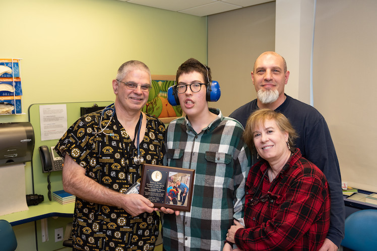 Nicholas, who has Prader-Willi syndrome, and his parents present an award to his nurse