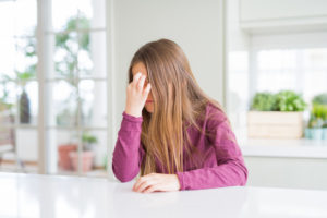 girl with chronic headache holds her head in pain