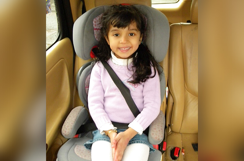 girl sitting safely in a booster seat