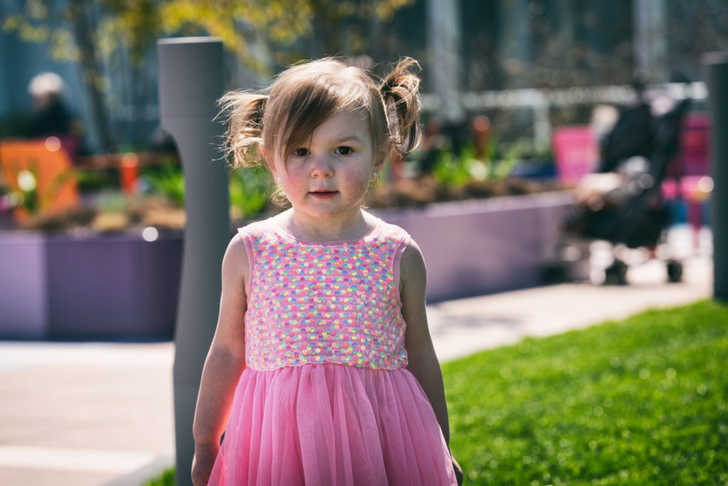 little girl with cdh poses in a garden