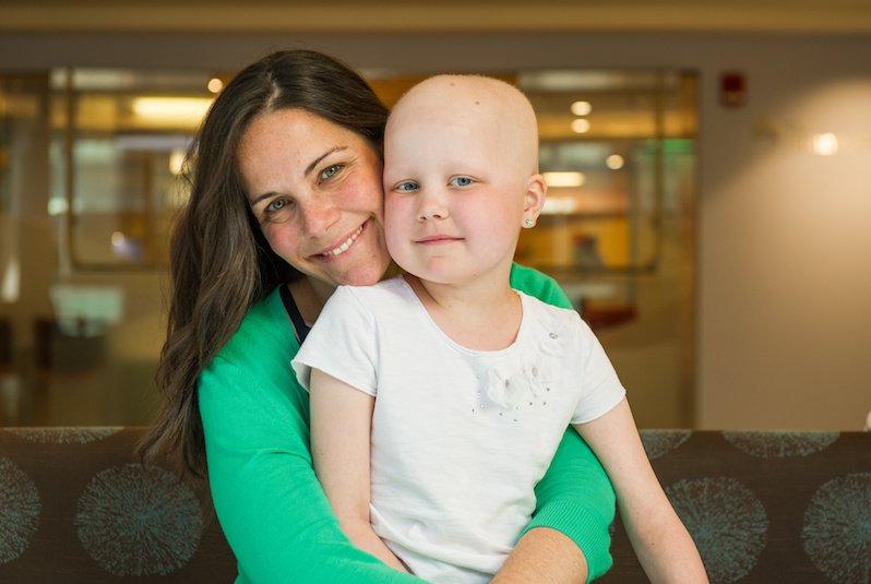 A pediatric leukemia patient is held by her mom