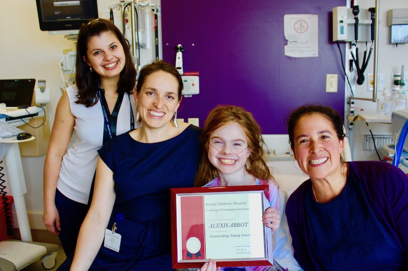 Lexi, who had complex spine surgery, receives a certificate of recognition from the TIDO team