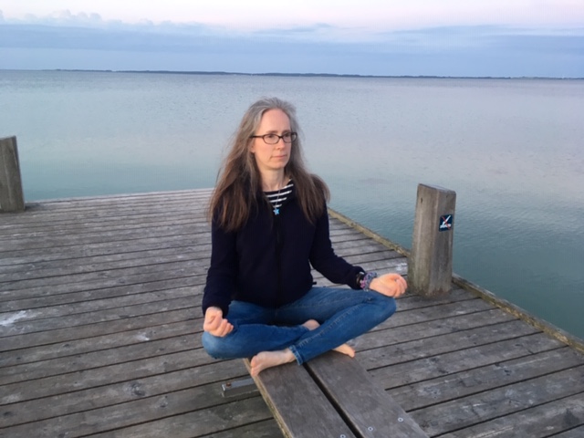 Emily Davidson meditates on a pier overlooking the water