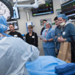 A clinician in a simulated operating room describes spinal fusion surgery for a group of patients and their families.