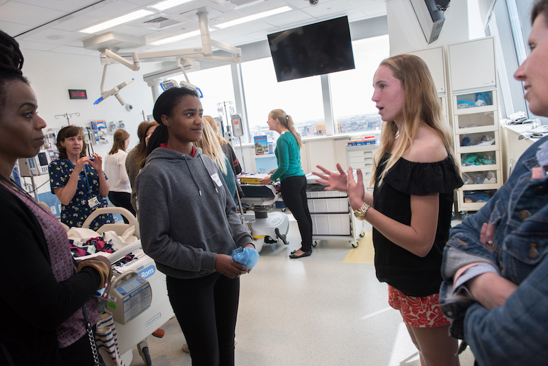 A patient who had spinal fusion surgery talks to another patient and her mother in the simulation lab. 