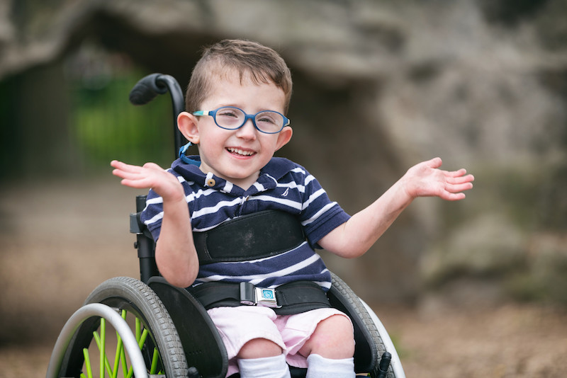 boy with spina bifida smiles in his wheelchair
