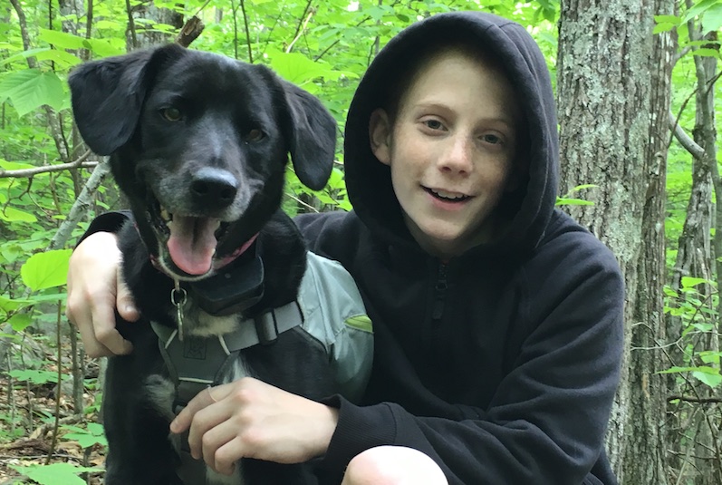 Gavin, who has Crohn's disease, in the woods with his dog
