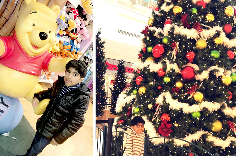 Saif, who was born with cervical spine deformity, poses next to a Winnie the Pooh statue and a large Christmas tree.