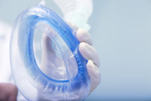 gloved hand holding anesthesia mask