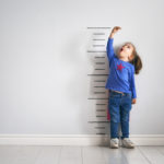 Child measuring herself against growth chart