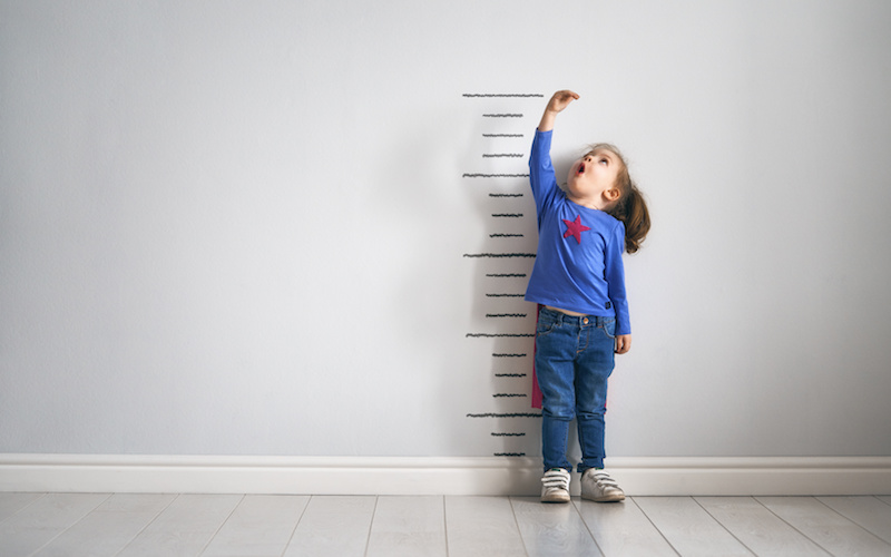 Child measuring herself against growth chart