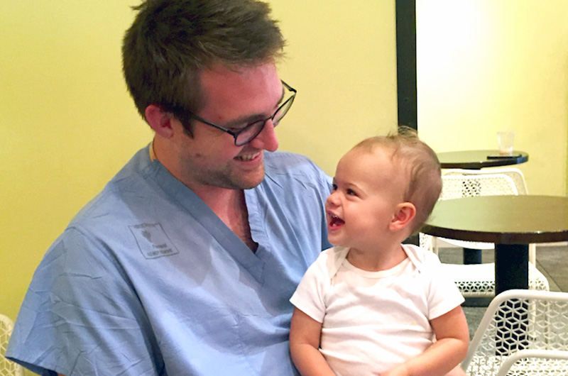 Dr. Birch, orthopedic doctor, and a toddler smile at each other.