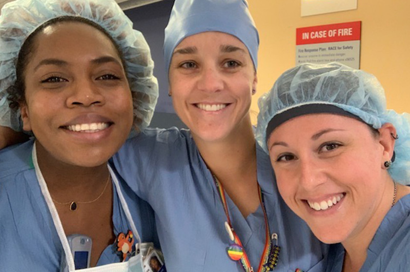 Dr. Heincelman, attending physician in orthopedic oncology, smiles for the camera along with two nurses. All three are wearing surgical scrubs