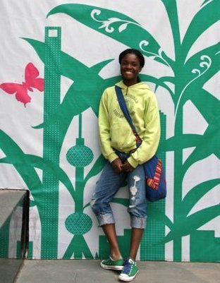 Louise, who had hip dysplasia and hip impingement, poses in front of a mural. Her feet turn outward. 