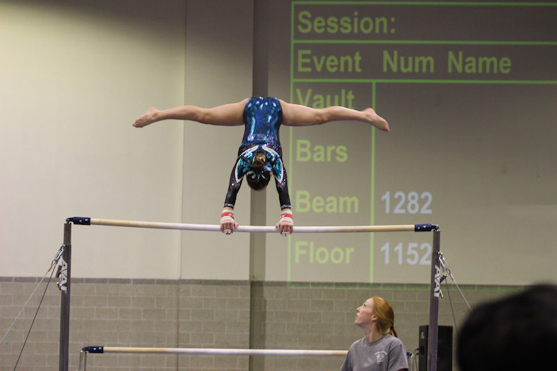 Mikayla, who was treated for hip avulsion fracture, balances upside down on the uneven bars.