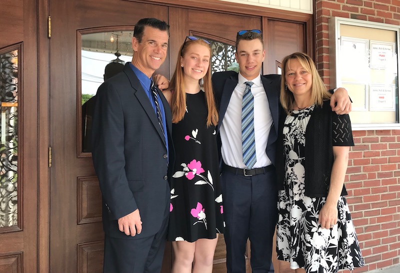 Nate and his family in dress clothes, pose in front of a banquet hall. 