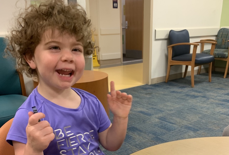 Ellery, who has opsoclonus myoclonus syndrome, laughs while waiting to see her doctor. 