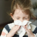 little girl with aerodigestive disorder is sneezing