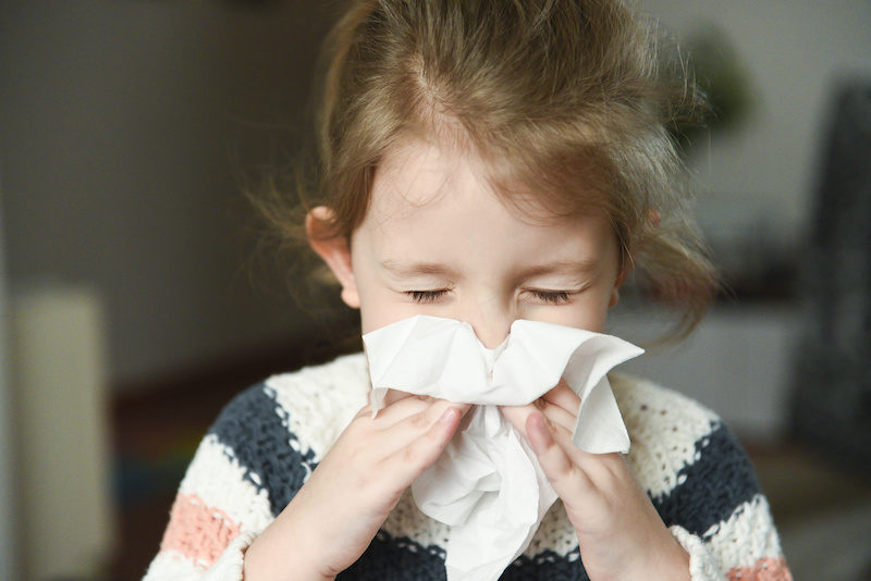 little girl with aerodigestive disorder is sneezing