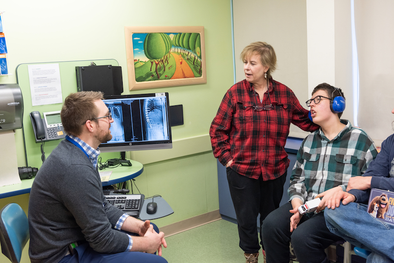 Dr. Birch, orthopedic surgeon, consults with family of patient who had spinal fusion surgery. 