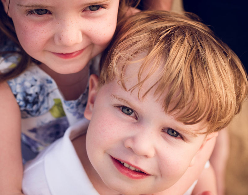 Colin, who has hemophilia, looks up at the camera as his sister hugs him.