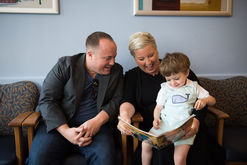 jack reads a book with his parents before having his g-tube removed