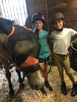 two kids pose with a horse at Camp Journey, a camp for kids with heart conditions