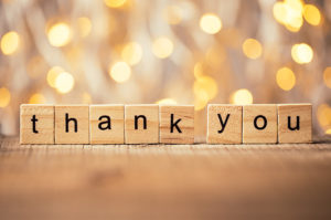 Blocks spell out thank you with lights in the background