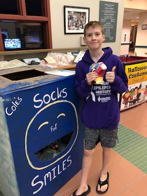 Cole, who has epilepsy, poses with a donation box for his sock drive