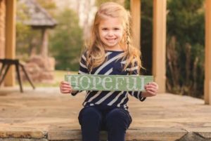 Libby, who had surgery to control her seizures, holds a sign that says "hopeful"