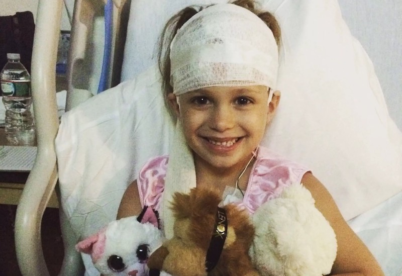 Libby, who had surgery to control her seizures, holds her stuffed animals in the hospital after her surgery