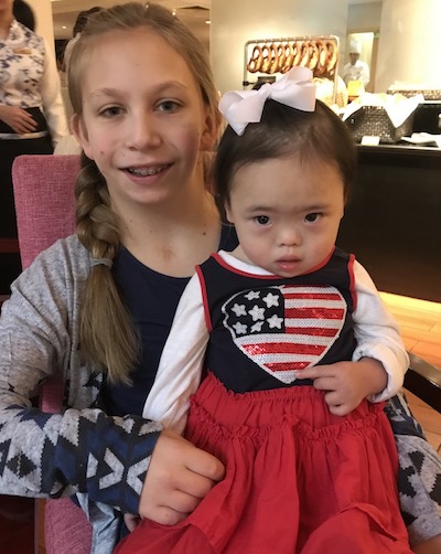 Everli, who has Down syndrome and atlantoaxial instability, sits on her sister's lap. 