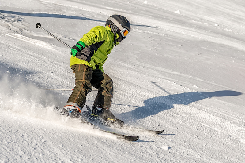A child skis down a slope, wearing a helmet. 