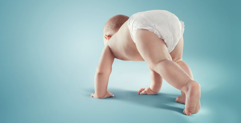 baby in a diaper crawling on floor