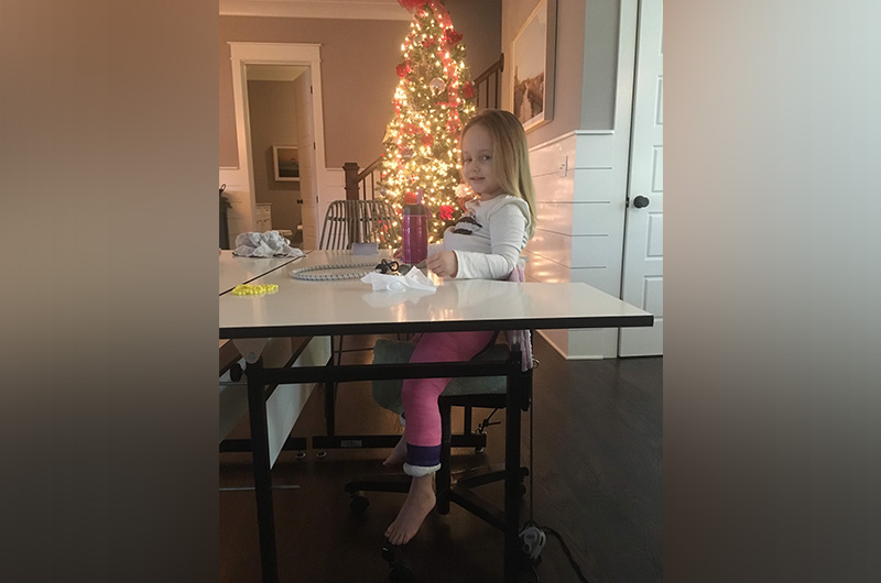 Emma, who had hip dysplasia, sitting at her spica cast table. 