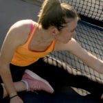 Female athlete stretches outside