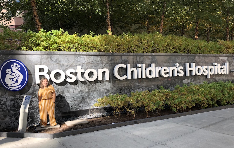 Maria, who had a severe leg length discrepancy, poses in front of a Boston Children's sign.