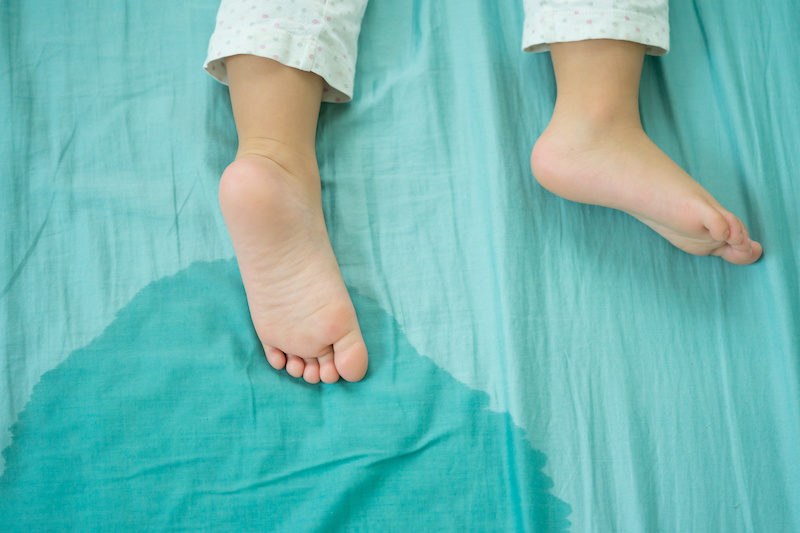 child's feet near puddle to show incontinence