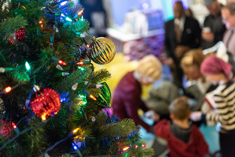 Patients in the hospital receive gifts under the lights of a Christmas tree