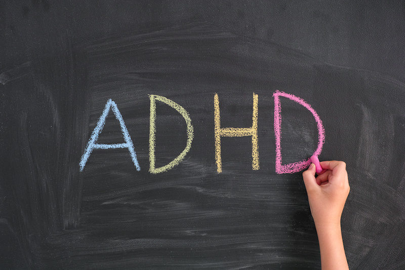 The letters "ADHD" written in chalk on a blackboard