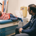Lamarcus, who has sickle cell, talks with his doctor in an exam room
