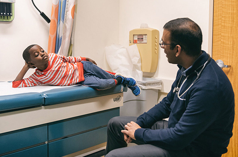 Lamarcus, who has sickle cell, talks with his doctor in an exam room